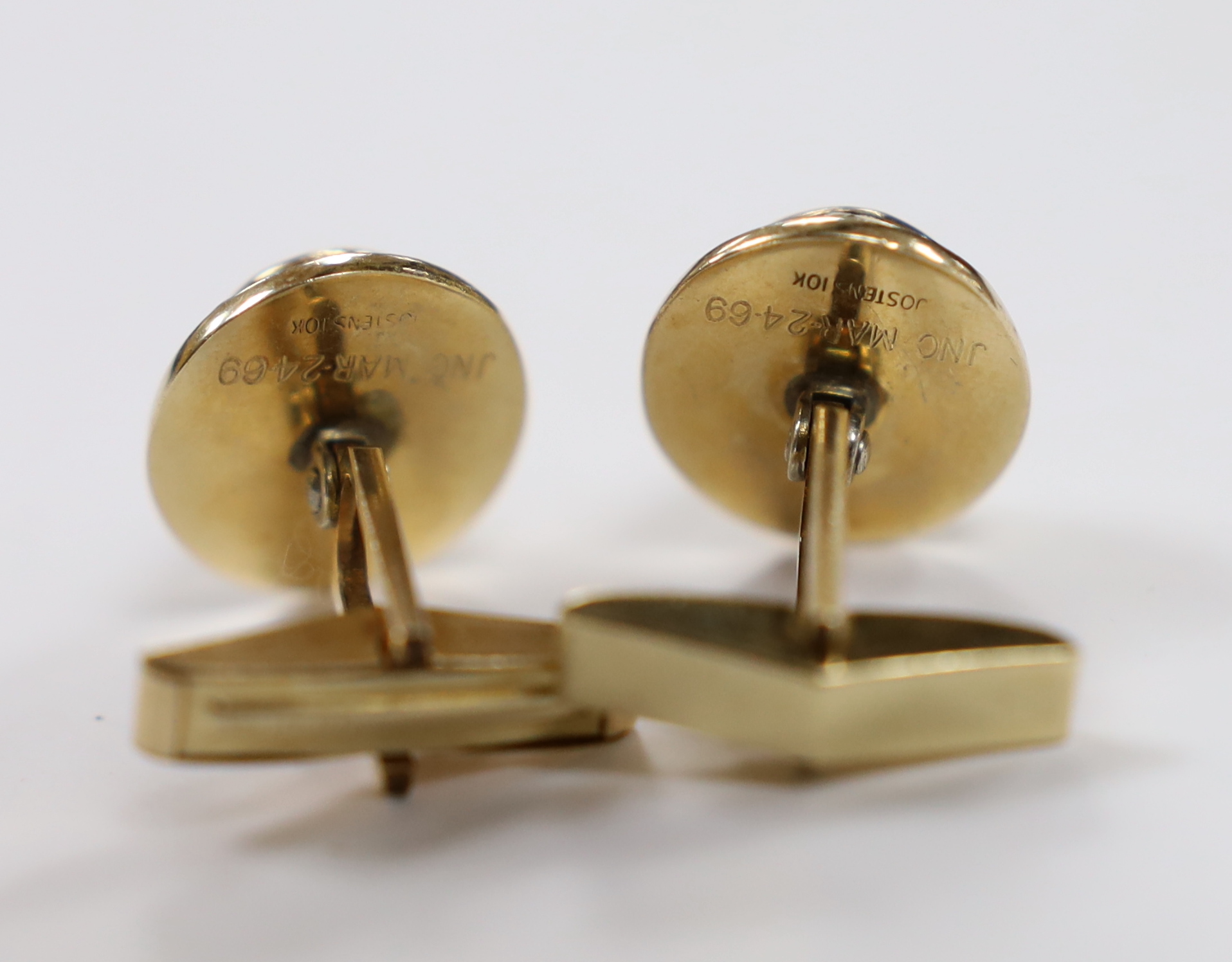A pair of yellow metal and blue cabochon paste set cufflinks, the backs inscribed 'Jostens 10k', the swivelling arms inscribed '1/20 12k G.F.'.